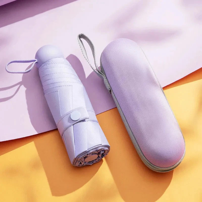A light purple compact 5-fold travel umbrella with a strap is shown on a yellow background.