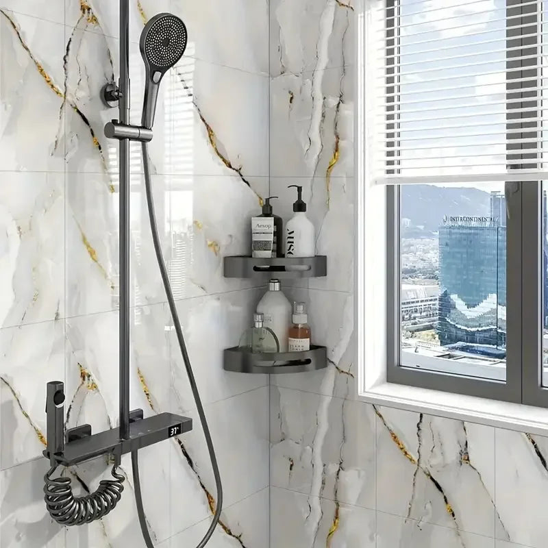 A shower fixture with a handheld sprayer and a wall-mounted soap dish is installed on a white marble tile wall.