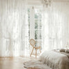White sheer ruffled lace curtains filter light through a window in a bright room.