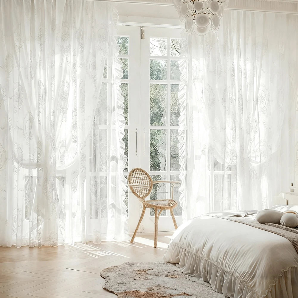 White sheer ruffled lace curtains filter light through a window in a bright room.