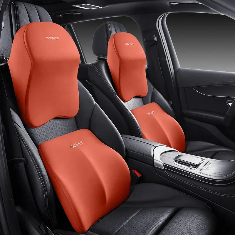 Orange memory foam car headrests and lumbar support pillows installed in a black car seat interior.