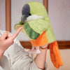 A hand puppet toy shaped like a green and gray parrot is being held by a person's hand.