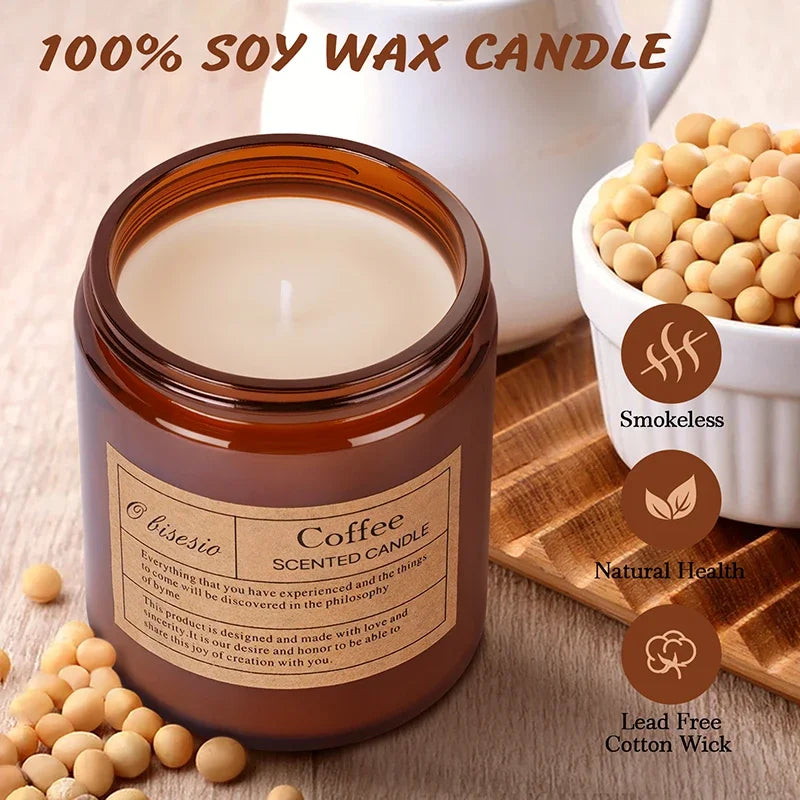 A brown glass jar of coffee scented soy wax candle sits next to a white ceramic pitcher and loose coffee beans.