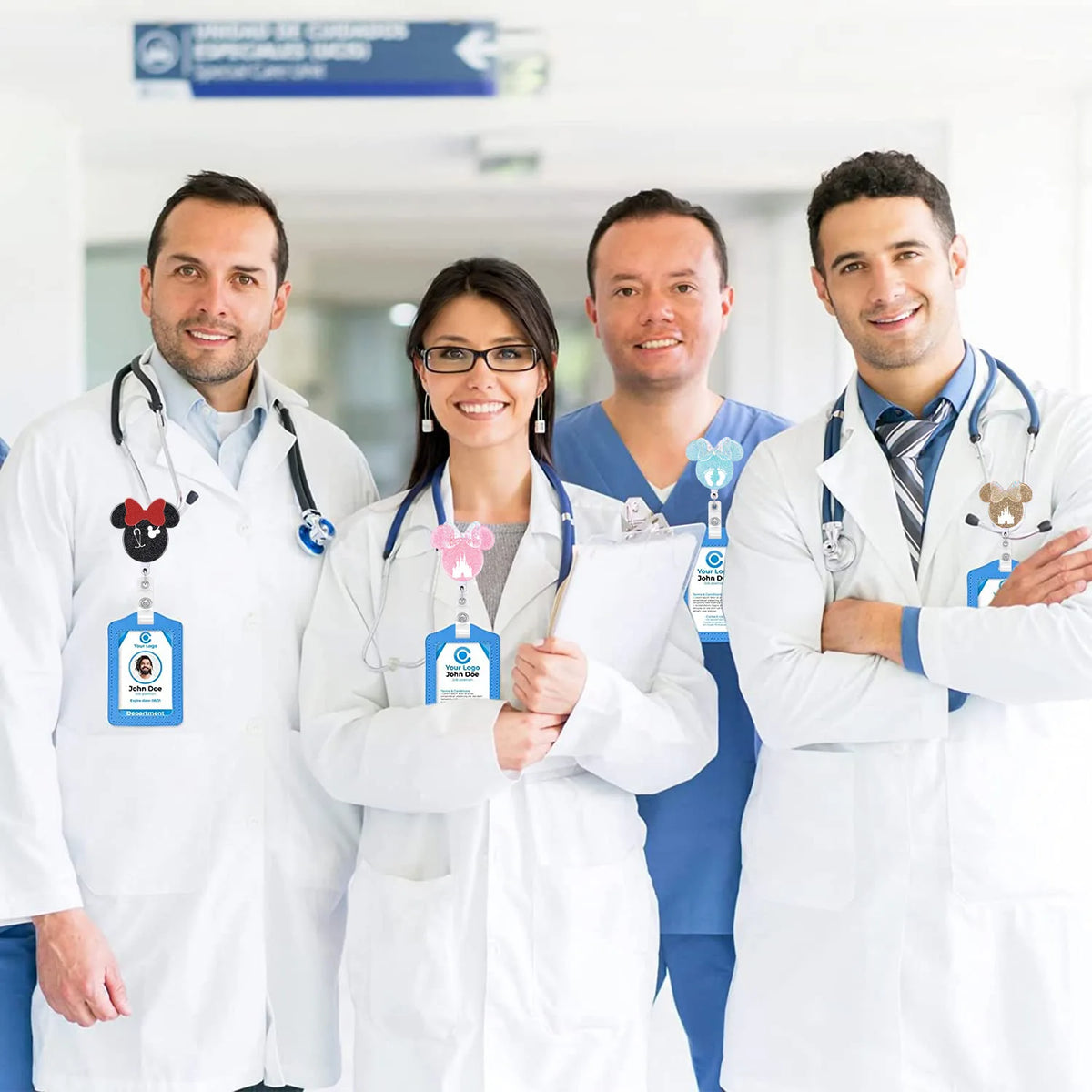 Four smiling nurses in white coats standing together with badge reels and ID holders.
