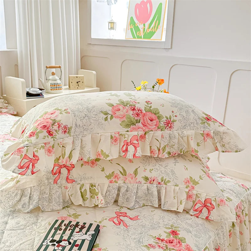 A set of two floral cotton pillowcases featuring pink roses and ribbons on a white background.
