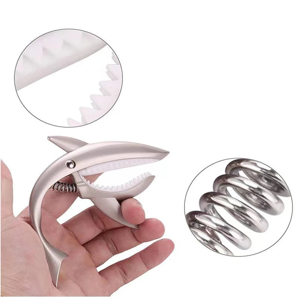 A hand holds a silver zinc alloy guitar capo, with inset images showing the cap and the tuning pegs.