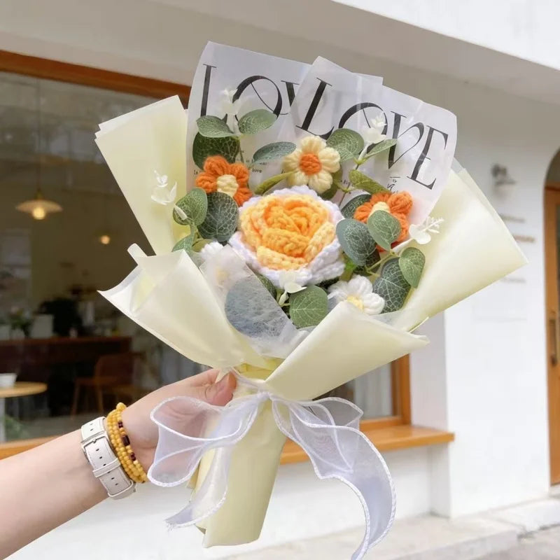 A bouquet of handmade crochet artificial flowers featuring orange and white blooms wrapped in sheer paper.