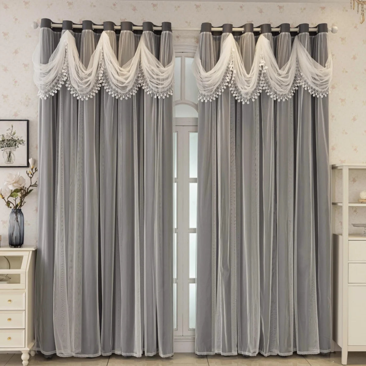 Gray sheer curtains with white trim and fringe hanging in a window frame.