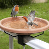 A small bird is splashing water on a copper disk bird bath cleaner with triple-point support.