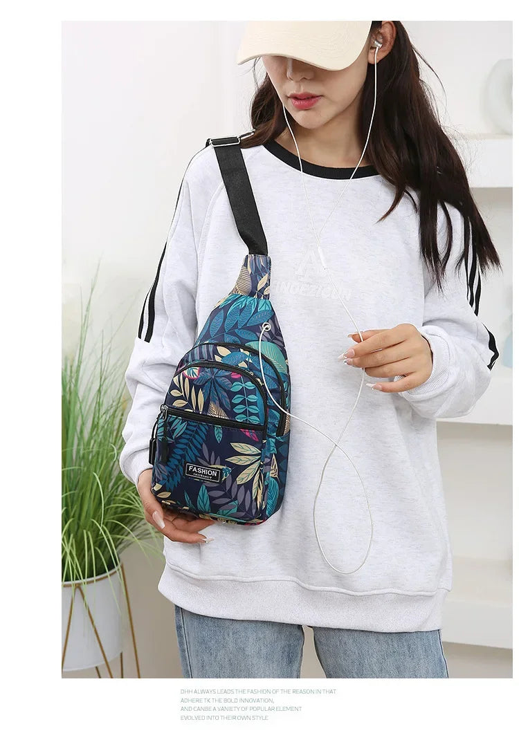 A woman wearing a light gray sweatshirt holds a colorful leaf print sling crossbody bag.
