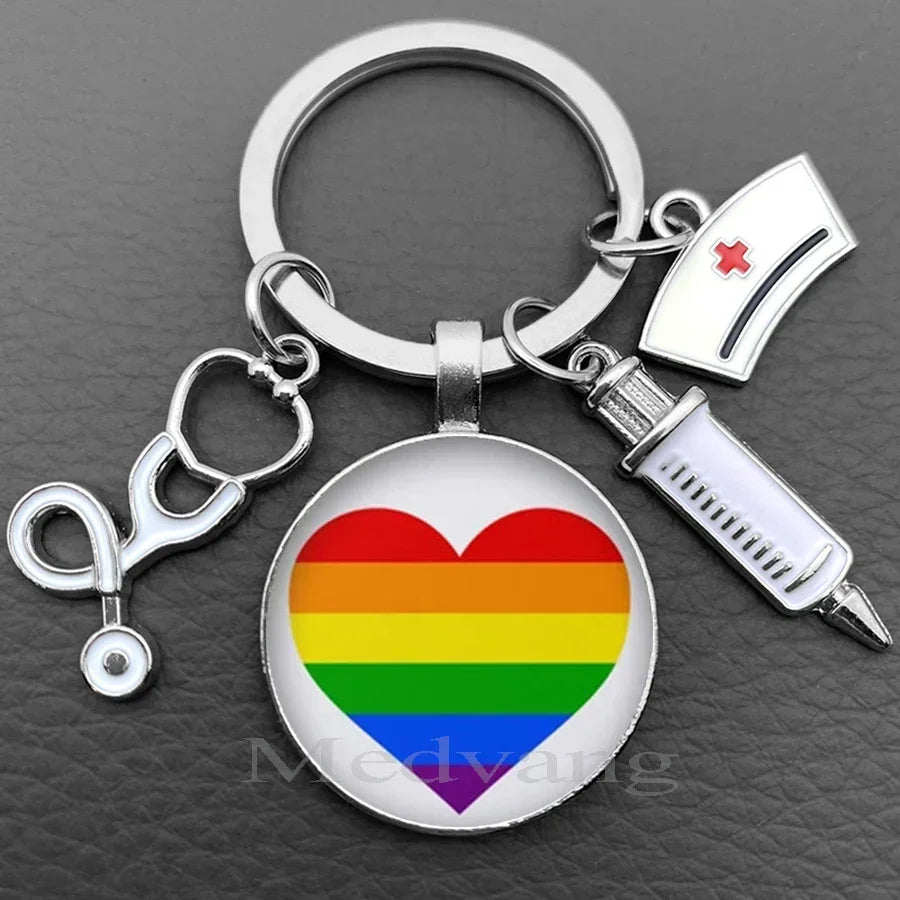Silver necklace keychain featuring a heart design with the rainbow flag and a medical syringe charm