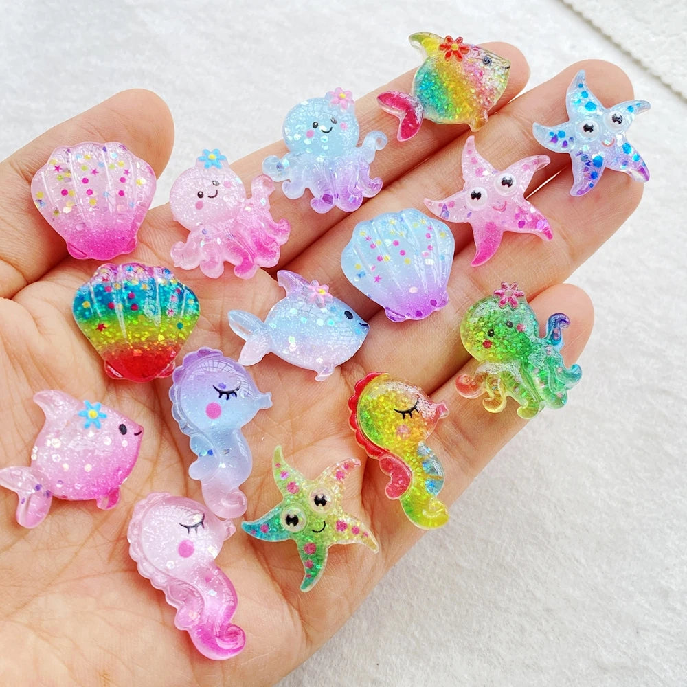 A hand holds various iridescent, colorful resin charms shaped like sea creatures and starfish for crafting.