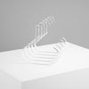 A silver metal hanger with multiple curved hooks is displayed on a white surface.