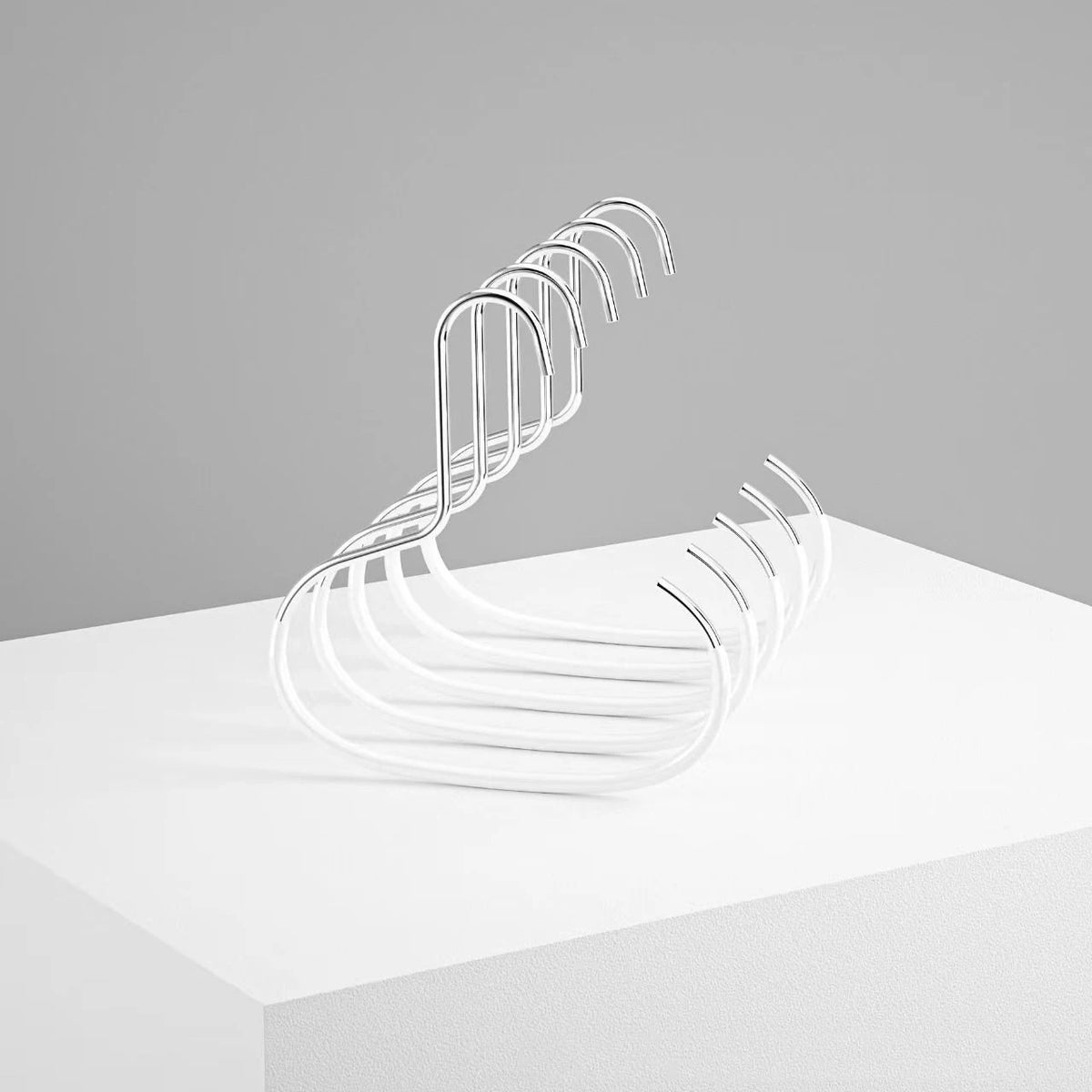 A silver metal hanger with multiple curved hooks is displayed on a white surface.