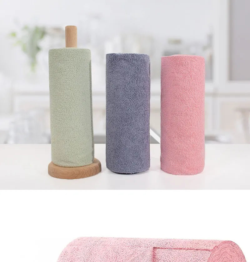 Three rolls of reusable microfiber cleaning towels in sage green, gray, and pink standing upright.