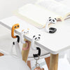 A set of cute animal-themed portable bag hooks made of silicone and plastic are displayed on a white table next to an open bo