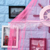 Pink lace canopy mosquito net draped over a window with framed pictures.