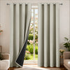 Light beige insulated blackout curtain panels with a black accent panel hanging in a window frame.