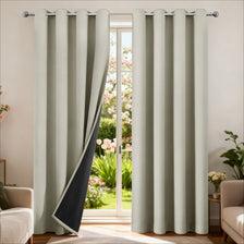 Light beige insulated blackout curtain panels with a black accent panel hanging in a window frame.
