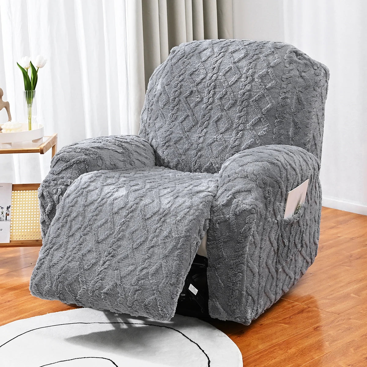 Housse de canapé jacquard grise décorative drapée sur un fauteuil dans une pièce lumineuse.