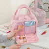 A pink large travel makeup bag with a wide opening is shown open, revealing makeup brushes and cosmetic tools.