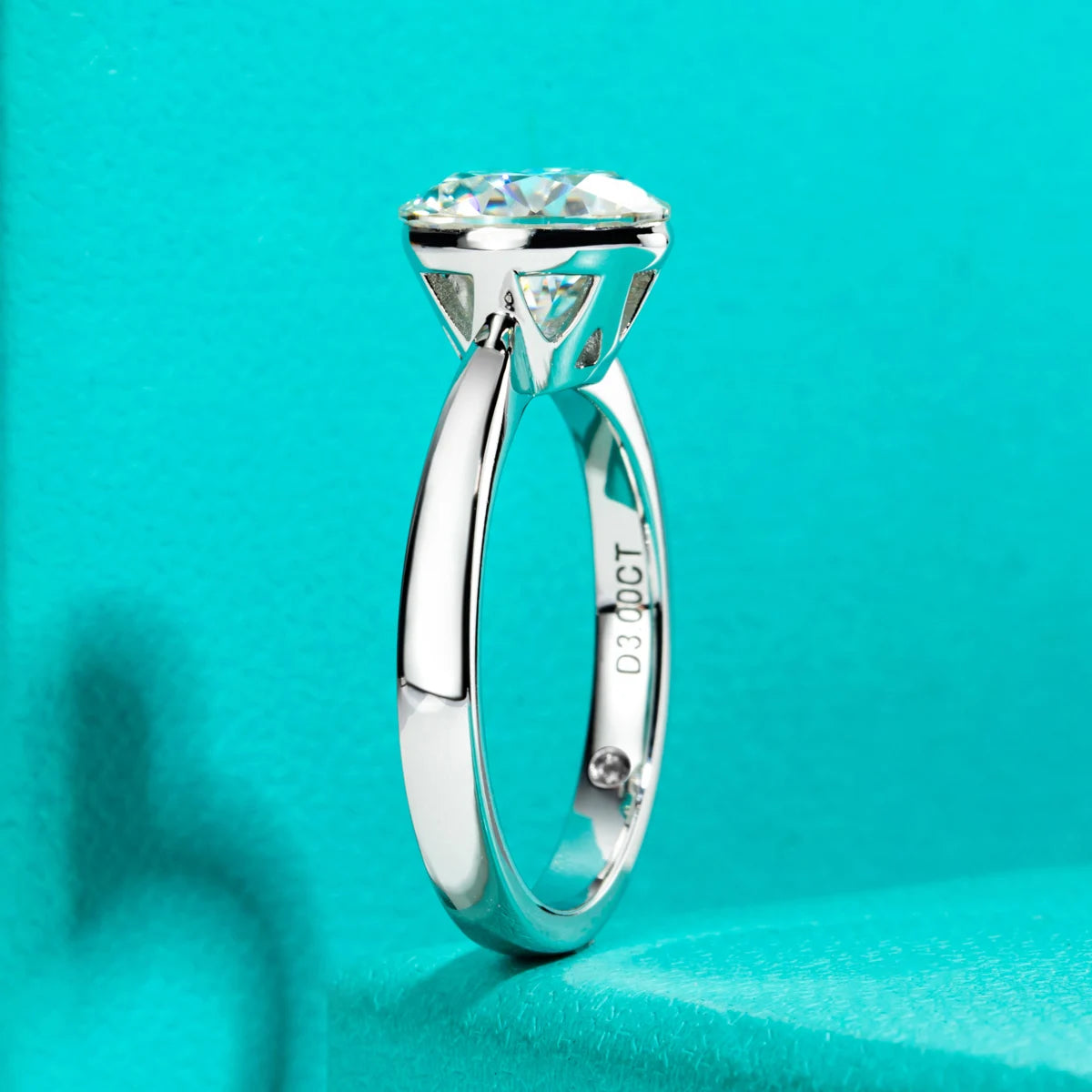 A close-up shot of a solitaire engagement ring featuring a brilliant clear stone set in a silver band against a turquoise bac