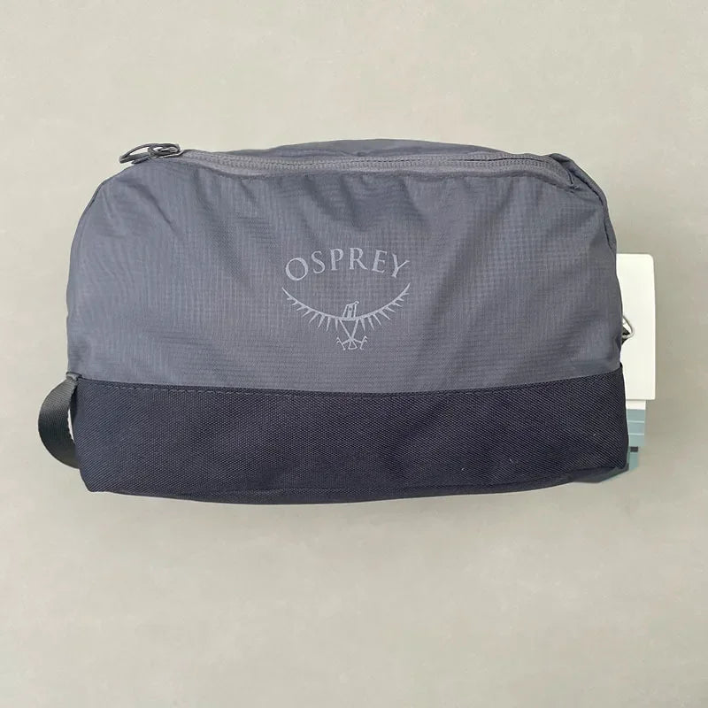Sac de toilette pliable et imperméable gris Osprey avec une section inférieure bleu marine.