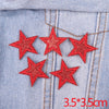 Set of five red glitter star iron-on embroidered patches on light blue denim fabric