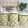 Three cream and gold checkerboard porcelain storage jars with gold lids