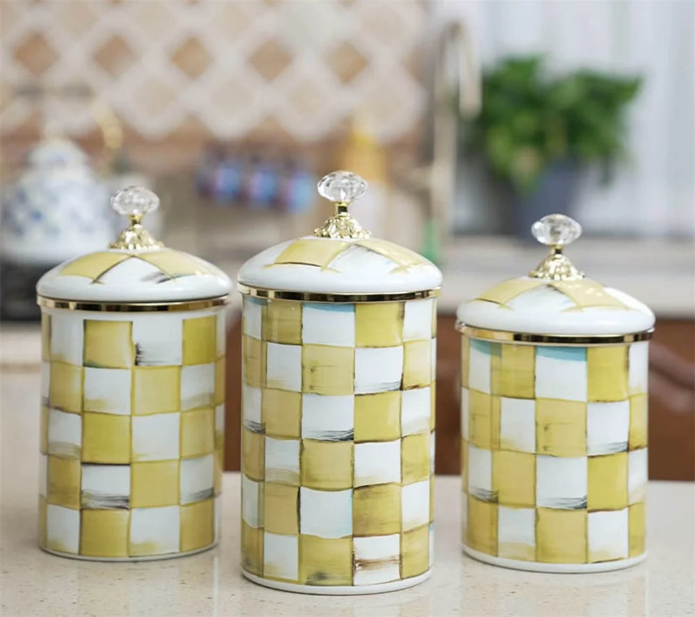 Three cream and gold checkerboard porcelain storage jars with gold lids