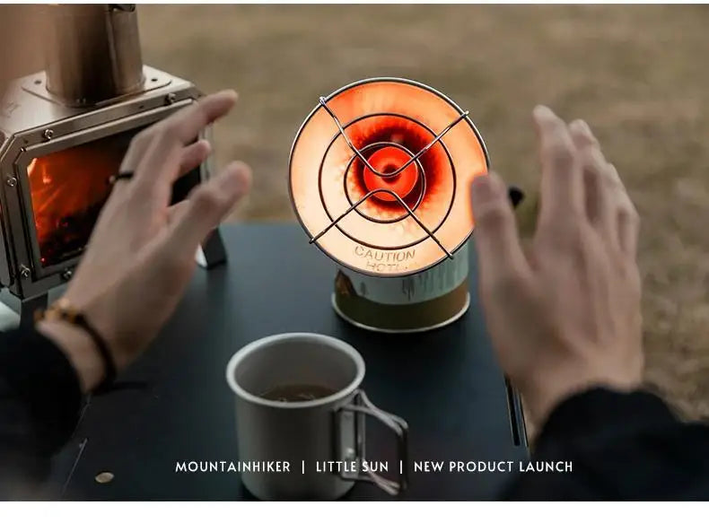 Hands hold a portable butane gas stove with a circular flame visible on the burner for a new product launch.