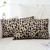 A close-up of a plush velvet leopard print pillowcase resting on a white sofa.