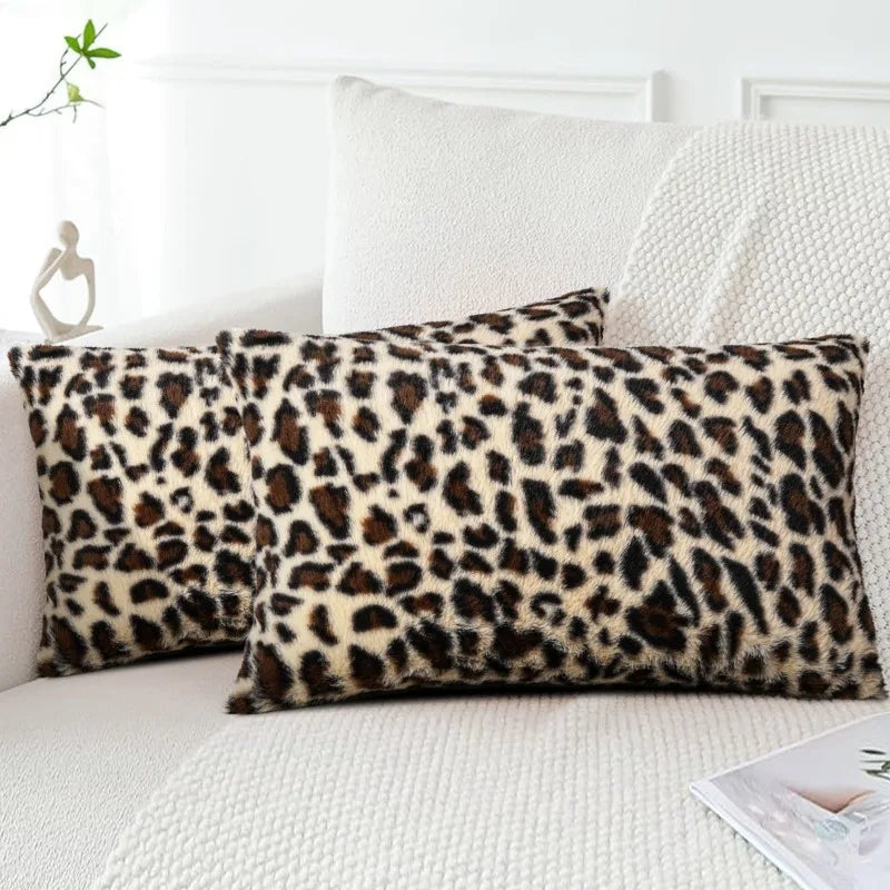 A close-up of a plush velvet leopard print pillowcase resting on a white sofa.