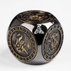 A dark, glossy metal spinner dice cube featuring intricate designs and a central symbol.