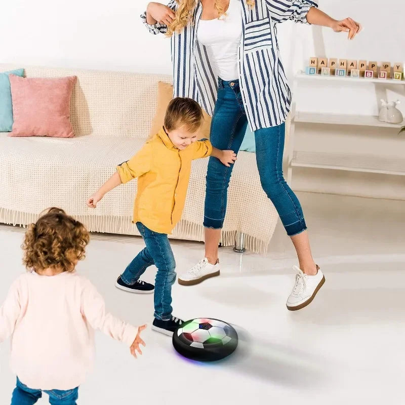 A woman is playing soccer with a young boy using an LED hover soccer ball.