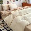 A beige duvet cover set with four pillows and a matching duvet is displayed on a bed.