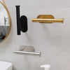 A close-up of a stainless steel self-adhesive toilet paper holder mounted on a white wall.
