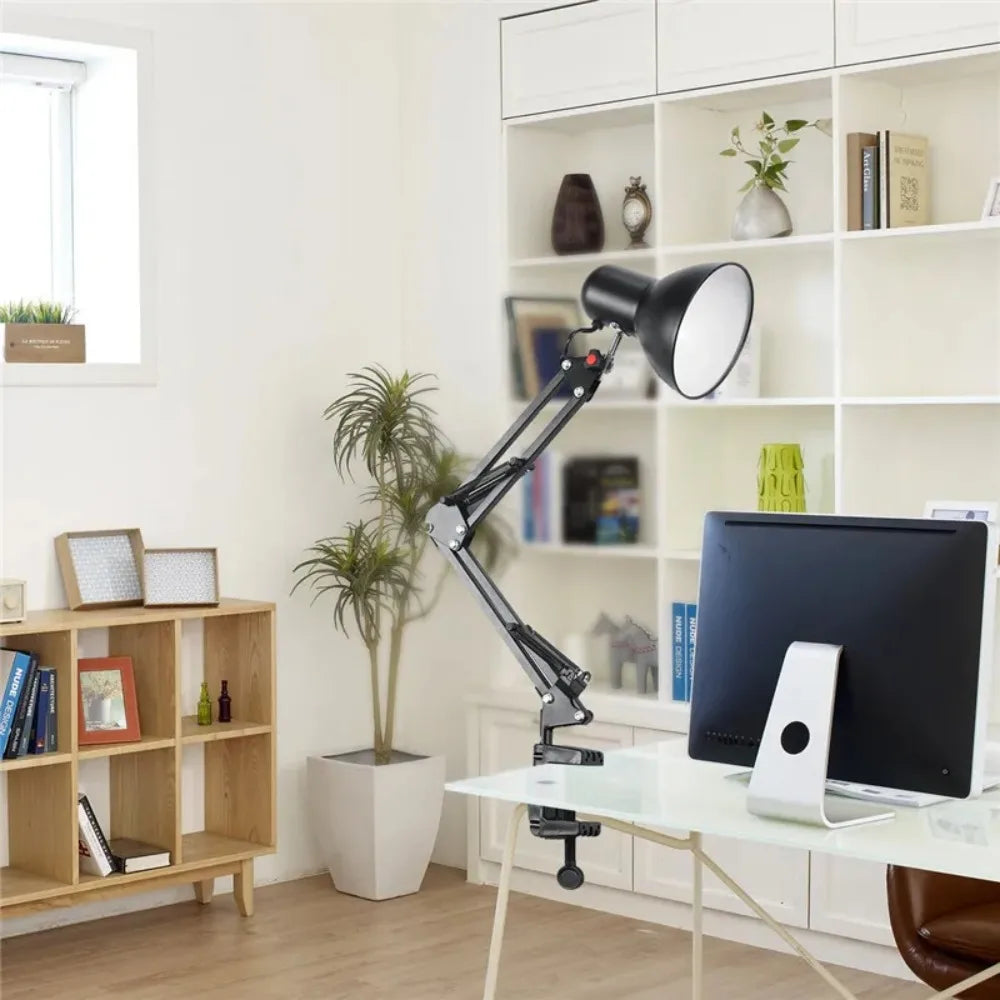 A black adjustable swing arm desk lamp is positioned over a white desk in a bright office setting.