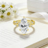A gold filled moissanite wedding ring with a marquise cut diamond set in a nature-inspired design resting on a white paper.