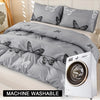 A gray duvet cover set with a butterfly print is displayed next to a white washing machine.