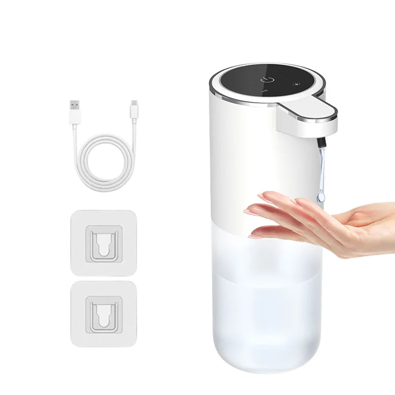 A hand is pouring liquid into a clear touchless automatic soap dispenser with a black pump and charging port visible.