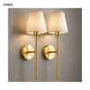 A pair of modern brass LED wall sconces with fabric shades mounted on a gray wall.