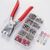 A red and silver snap fastener kit with hand press pliers is displayed in a clear plastic storage case.