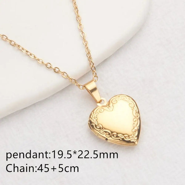 Gold heart pendant necklace with a delicate chain resting on a white surface.