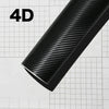 A close-up view of a black carbon fiber vinyl wrap film displaying a textured pattern on a grid background.