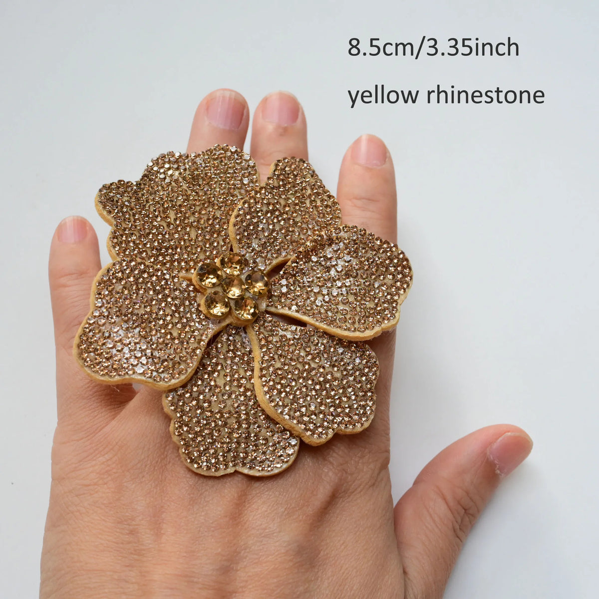 A hand holds a yellow rhinestone flower sew-on patch, measuring 8.5cm or 3.35 inches.