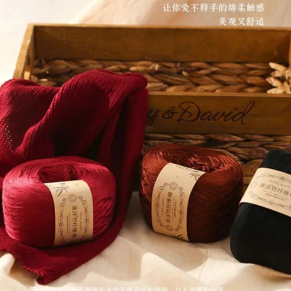 A stack of deep red yarn is displayed in a wooden box with straw bedding, ready for knitting or crochet.