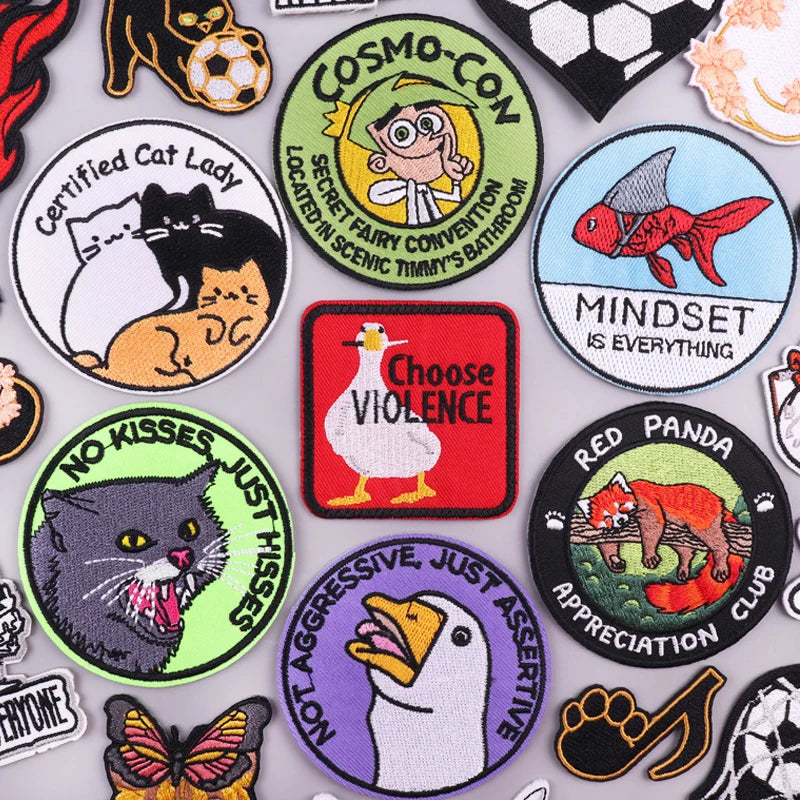 A collection of embroidered iron-on patches featuring funny cartoon and animal designs like a cat lady, a red fish, and a pan