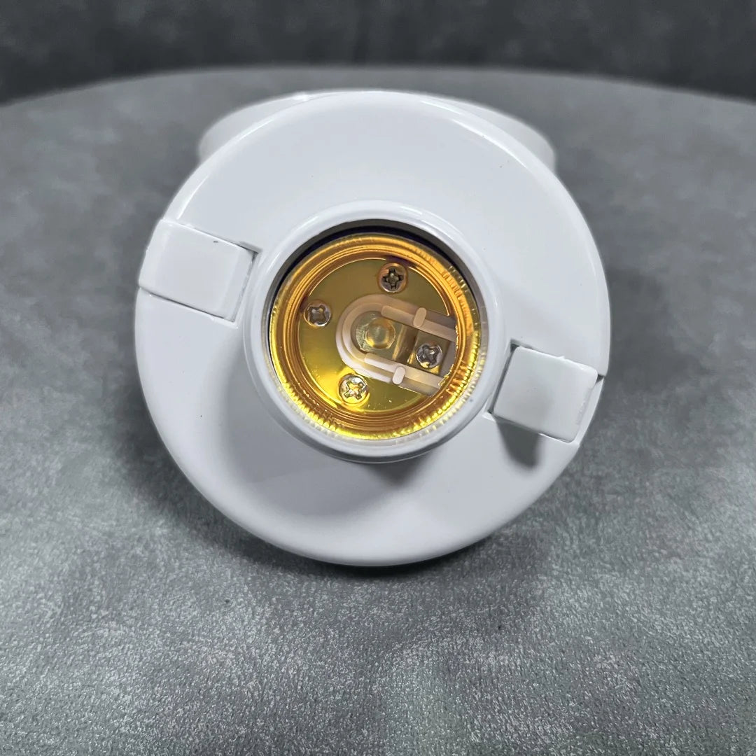 A white E27 screw cap light bulb holder with a brass-colored socket is shown on a gray surface.
