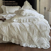 White ruffled duvet cover set with matching pillowcases displayed on a bed.